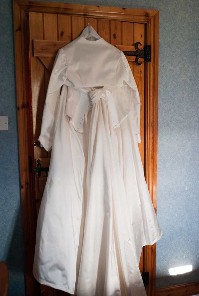 The bride's dress hung on a wooden door at Simonstone Hall Hotel