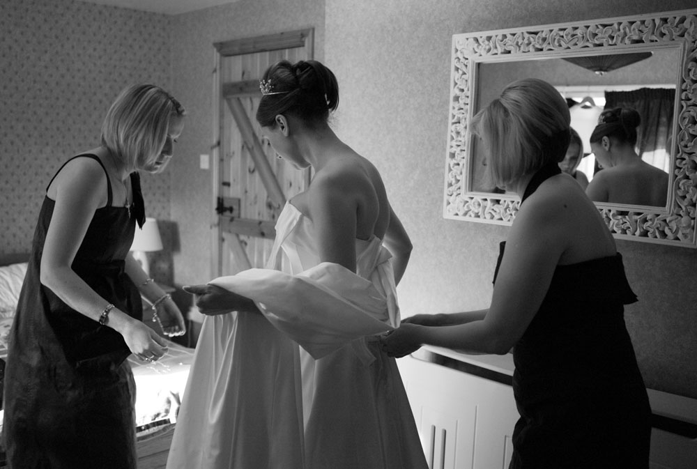 The bride being helped into her dress by her bridesmaids