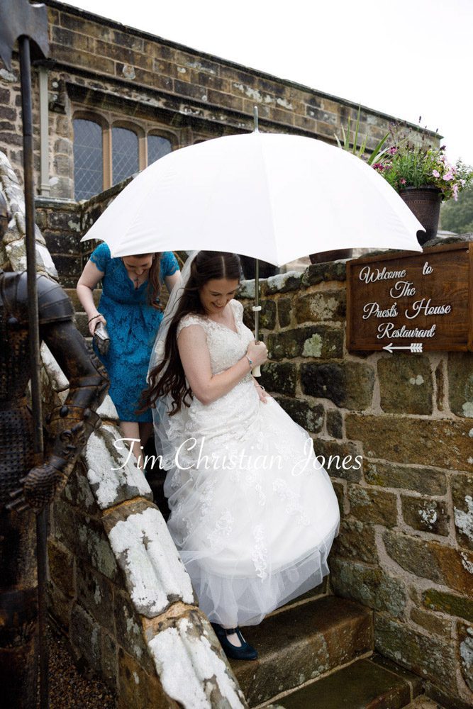 Bride holding white umbrella on rainy wedding day at The Priests House.