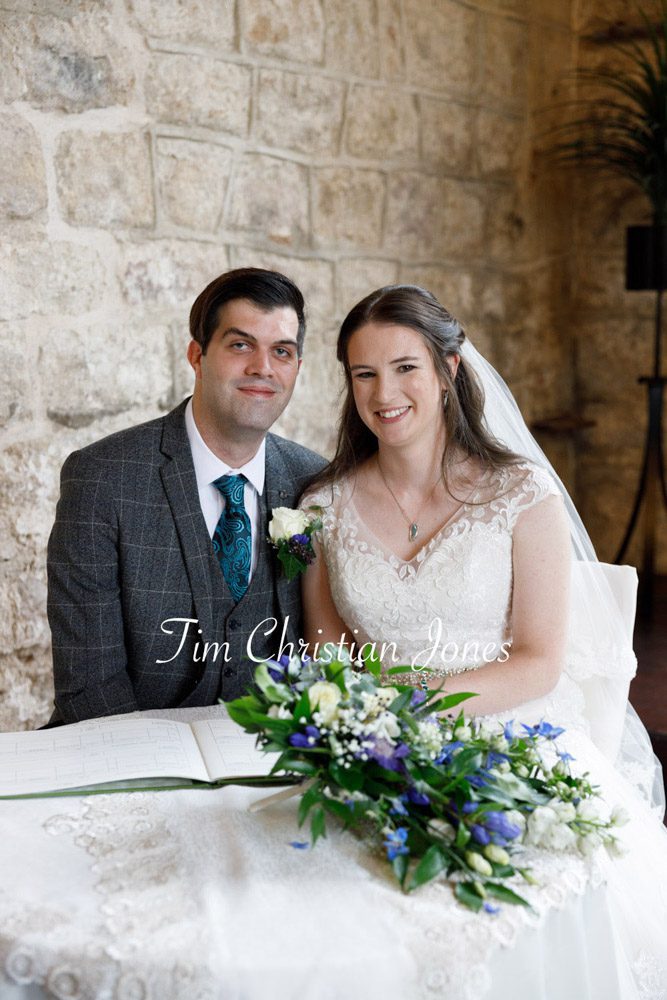 Bride and groom smiling by the wedding register table at The Priests House
