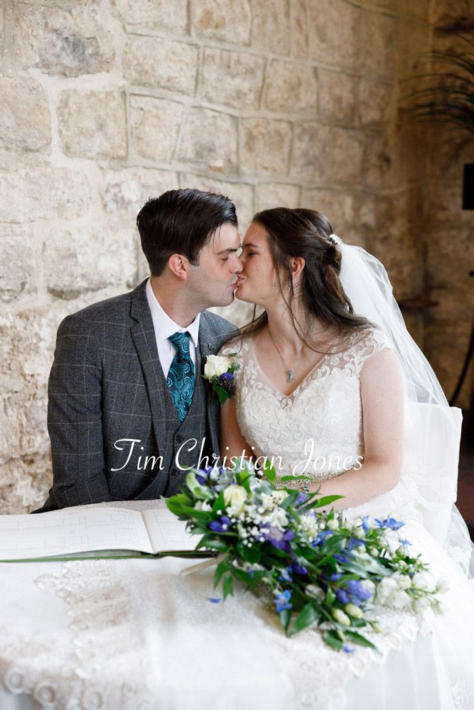 Romantic Yorkshire wedding moment as the couple kiss by the register table.