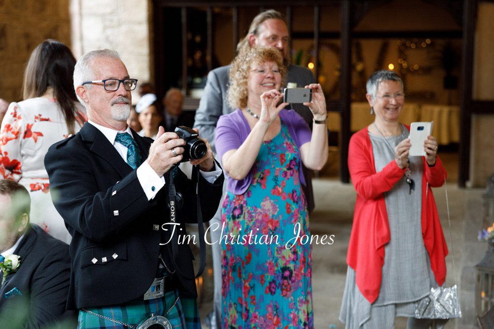 Guests capturing a sweet wedding moment with the couple and pageboy.