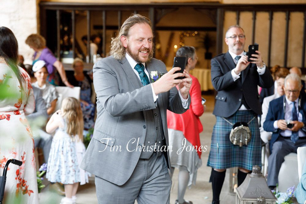 Best man capturing a special wedding moment with the couple and pageboy.