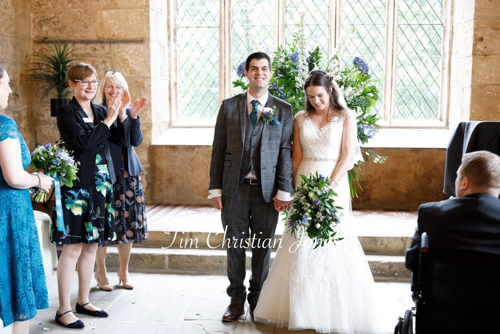 Guests clap as the shy bride and groom stand together before exiting the ceremony at The Priests House.