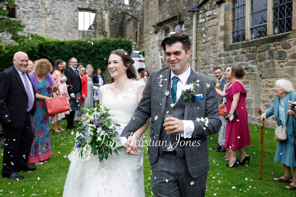 Bride and groom smiling under confetti.