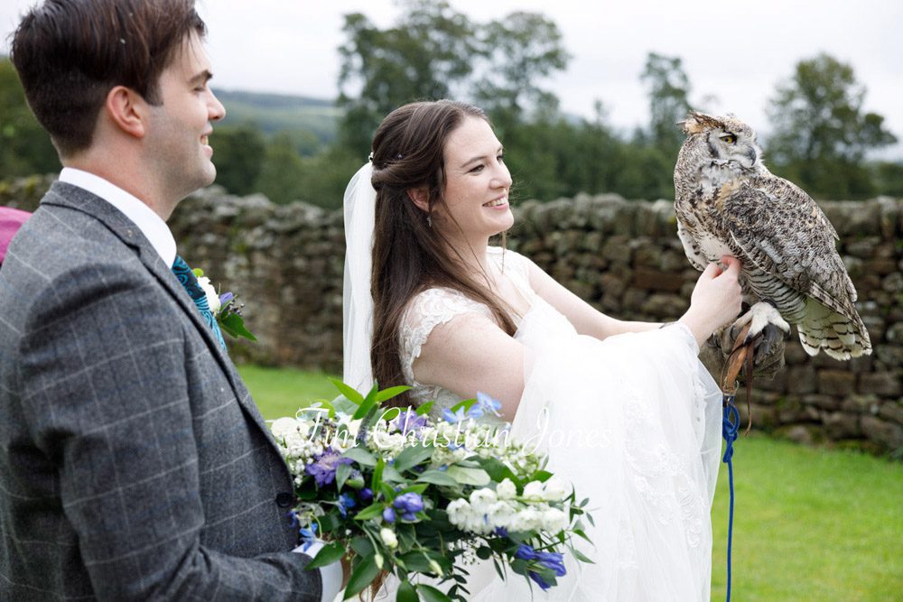 Bride holding a large owl with groom smiling at The Priests House.