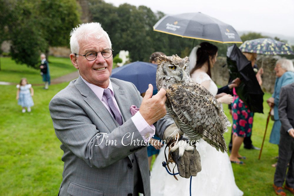 Candid moment of the groom's father holding an owl at The Priests House wedding.