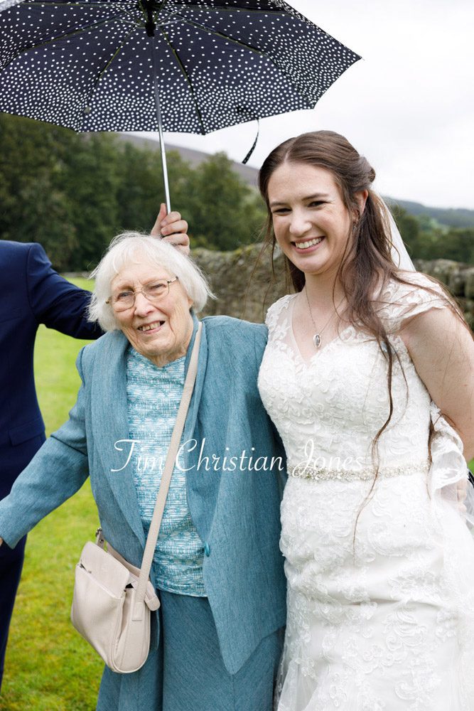 heartwarming rainy day wedding photo of the bride and her grandmother