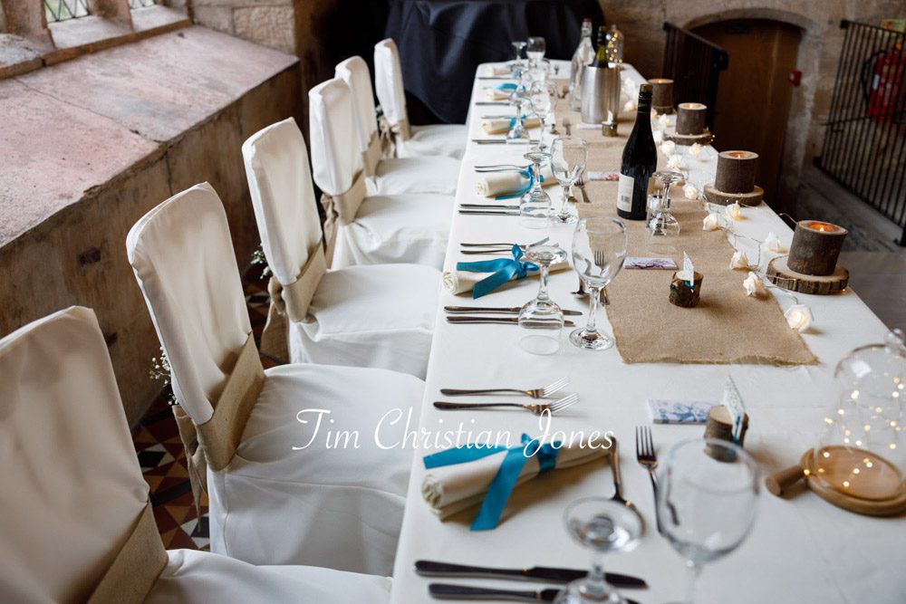 Elegant top table detail with natural wood candles and blue ribbon accents