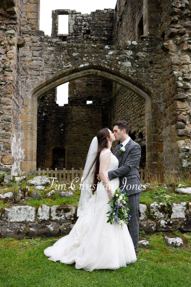 Bride and groom pose by the historic tower ruins at Barden Tower wedding.