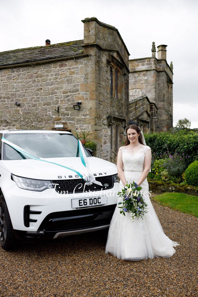 Elegant wedding photo of bride beside car.
