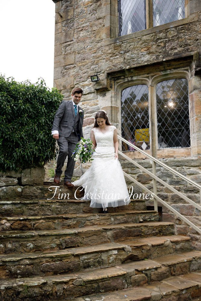 Romantic moment as newlyweds walk down stone steps at Barden Tower.