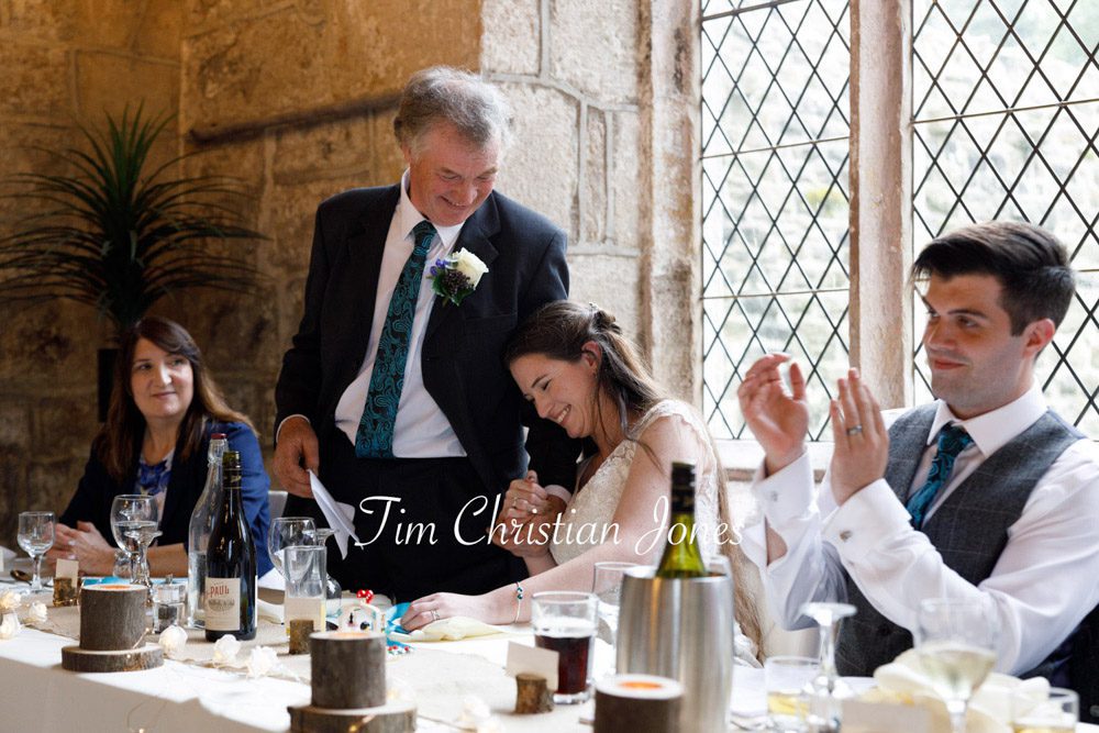 Tender moment as bride leans into her father during wedding toast.