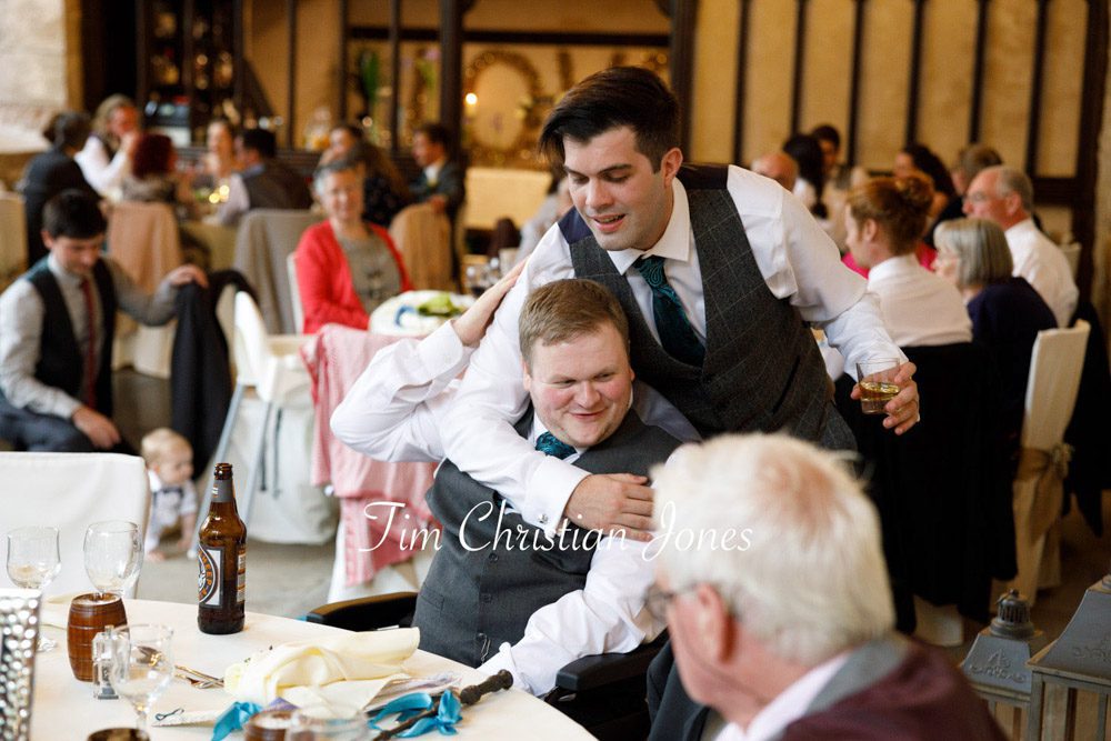 Candid hug between groom and best man at Barden Tower wedding.
